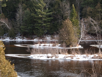 [Two small islands side by side in the river. The only ice built up is a triangular shape on the downstream side of the islands.]